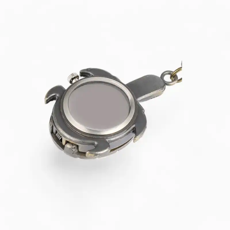Montre à gousset vintage en forme de tortue avec coque en métal argenté sur fond blanc.