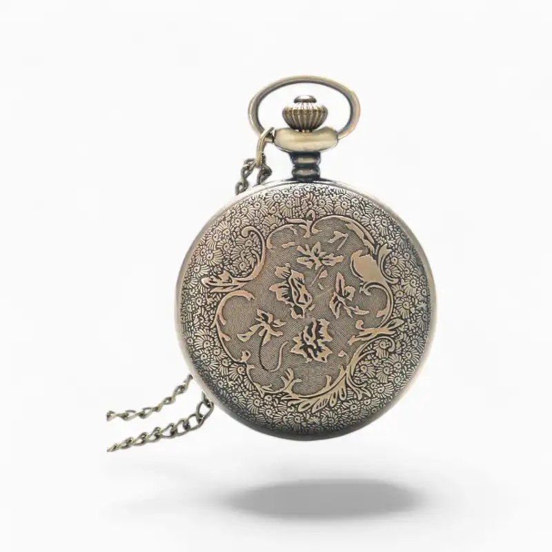 Montre à gousset vintage "L'Horloger" avec chaîne et gravure élaborée de style floral sur fond isolé.