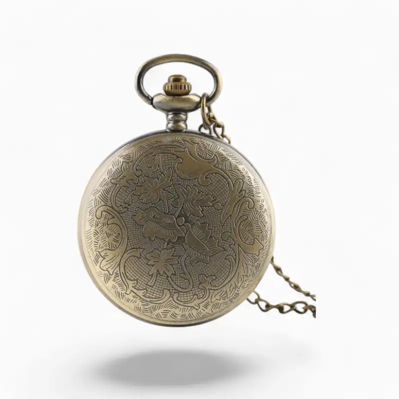 Montre à gousset vintage avec chaîne en or vieilli, présentant un motif complexe de lotus vert gravé sur le couvercle, sur fond blanc.