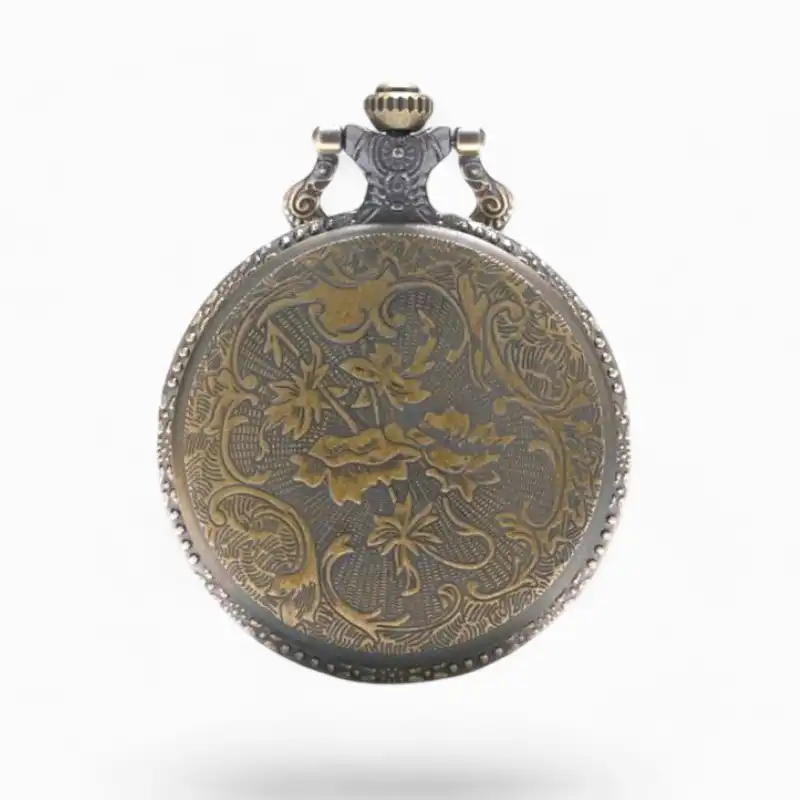 Montre à gousset vintage en métal avec gravures florales et motif tête de mort sur fond sombre.
