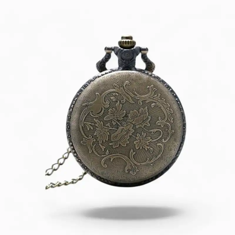 Montre à Gousset vintage en métal avec motifs floraux en relief et chaîne, fond blanc.