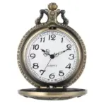 Montre à gousset vintage inspirée de la Reine Victoria avec un cadran blanc, chiffres noirs et détails ornementaux dorés, sur un fond neutre.