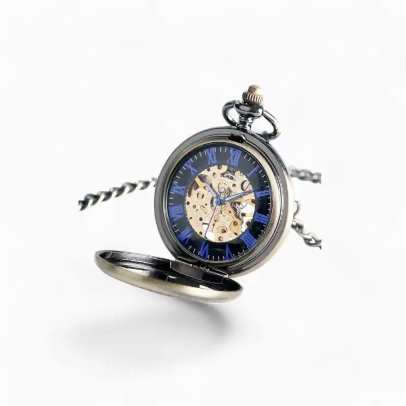 Montre à gousset mécanique noire avec détails floraux et aiguilles bleues, chiffres romains et mécanisme visible.