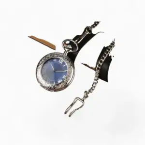 Montre à Gousset mécanique SKY Blue élégante avec cadran bleu et chiffres romains, boîtier gravé en argent, posée sur une surface en bois à côté d'un livre et d'un smartphone.